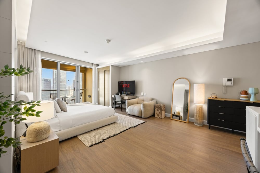 Studio bedroom with king bed, TV, mirror and dresser