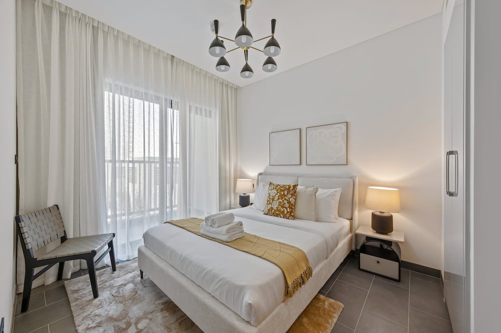 Bright bedroom with double bed balcony and chandelier
