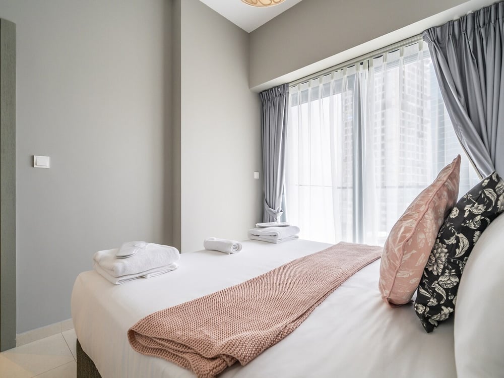 Bedroom with double bed and curtained balcony window