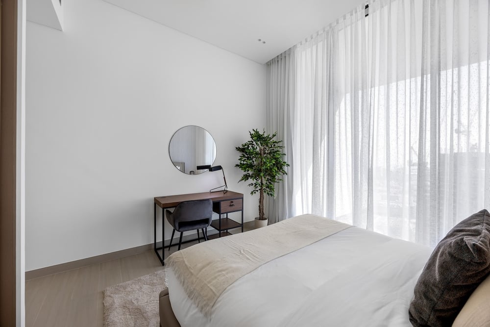 Bedroom with double bed, desk, mirror and floor-to-ceiling curtains