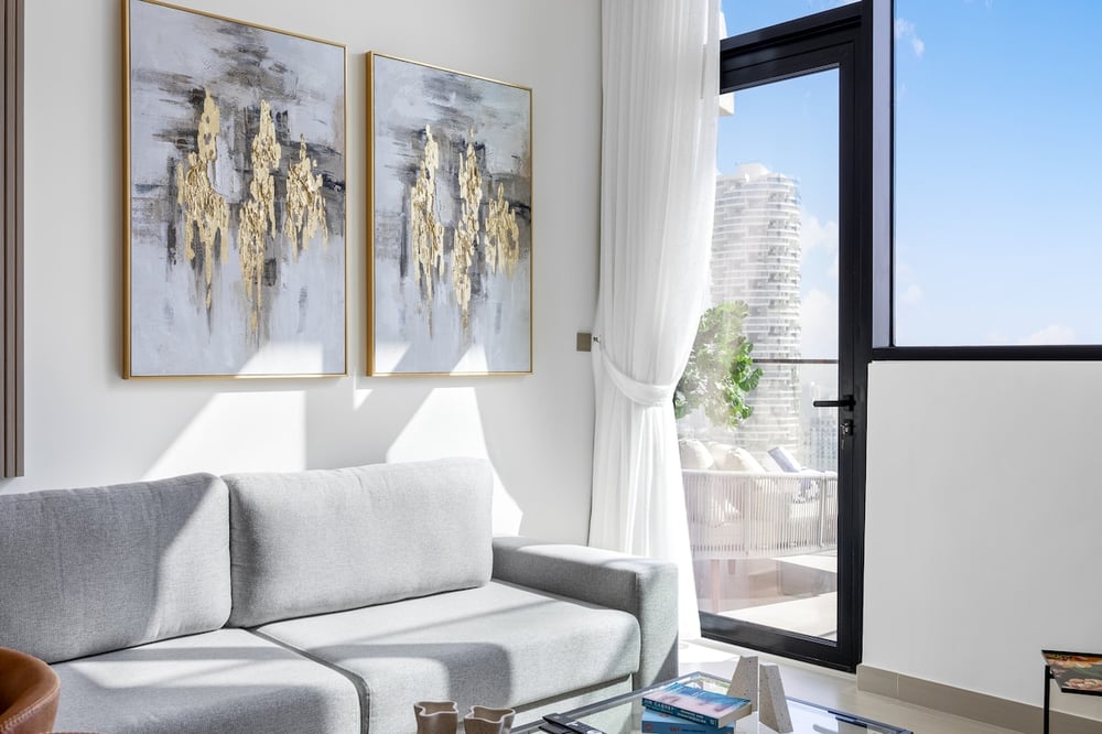 Living area corner with sofa and large window with balcony door