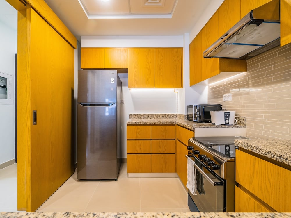 Kitchen with yellow cabinets fridge and gas stove