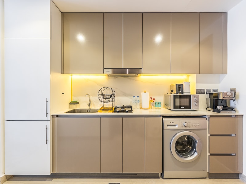 Studio kitchen with cabinets fridge and washing machine