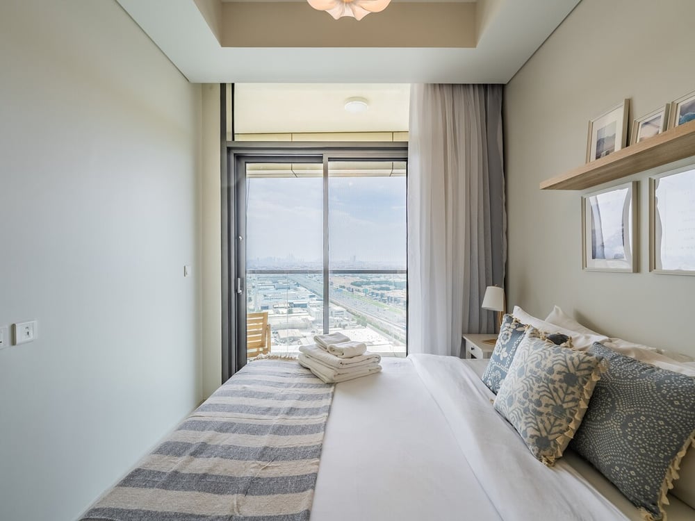 Bedroom with double bed and large window with city sea view