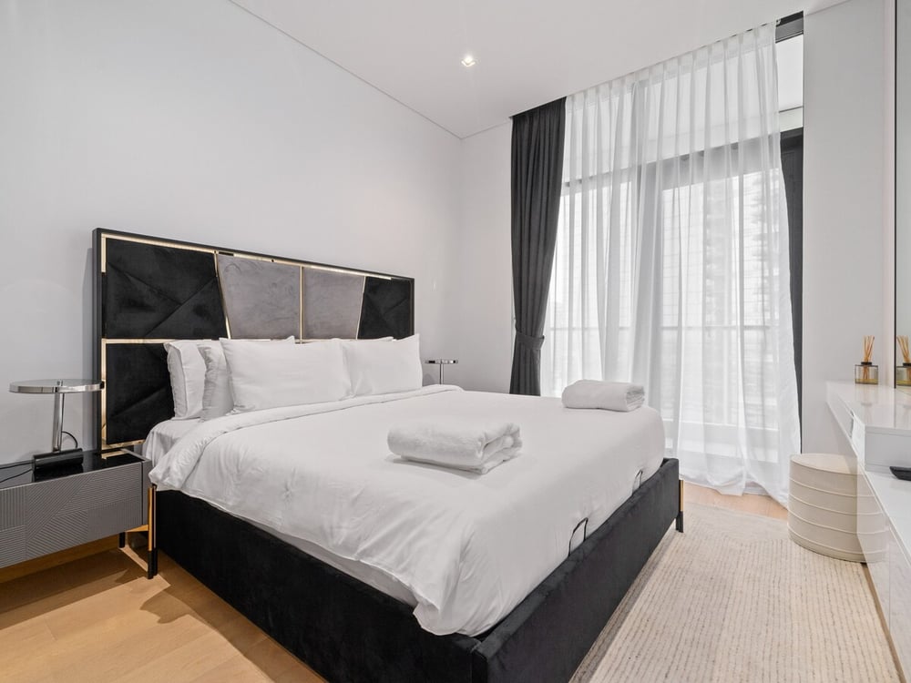 Bedroom with king bed, dark headboard and large window