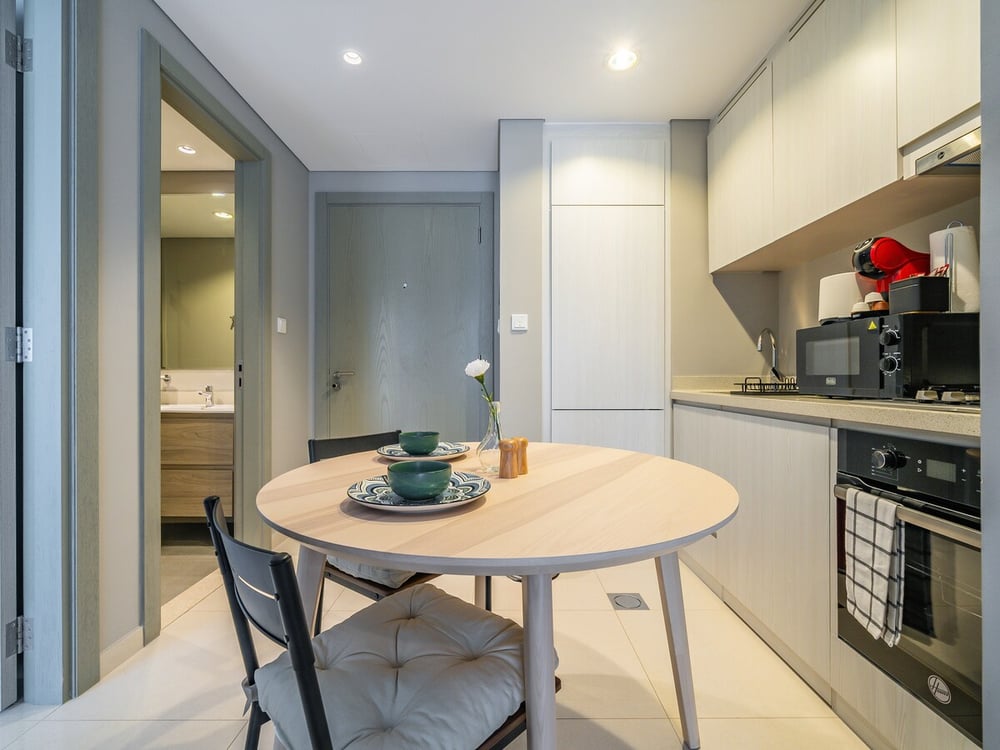 Dining area with round table and kitchen alongside