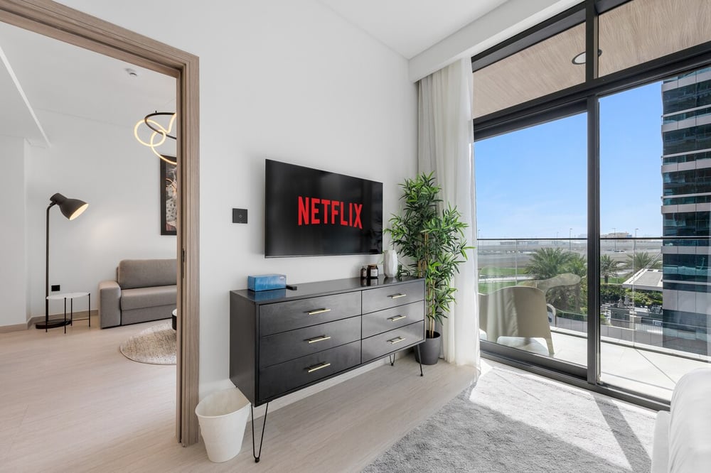 Living area with Netflix TV, dresser and balcony door