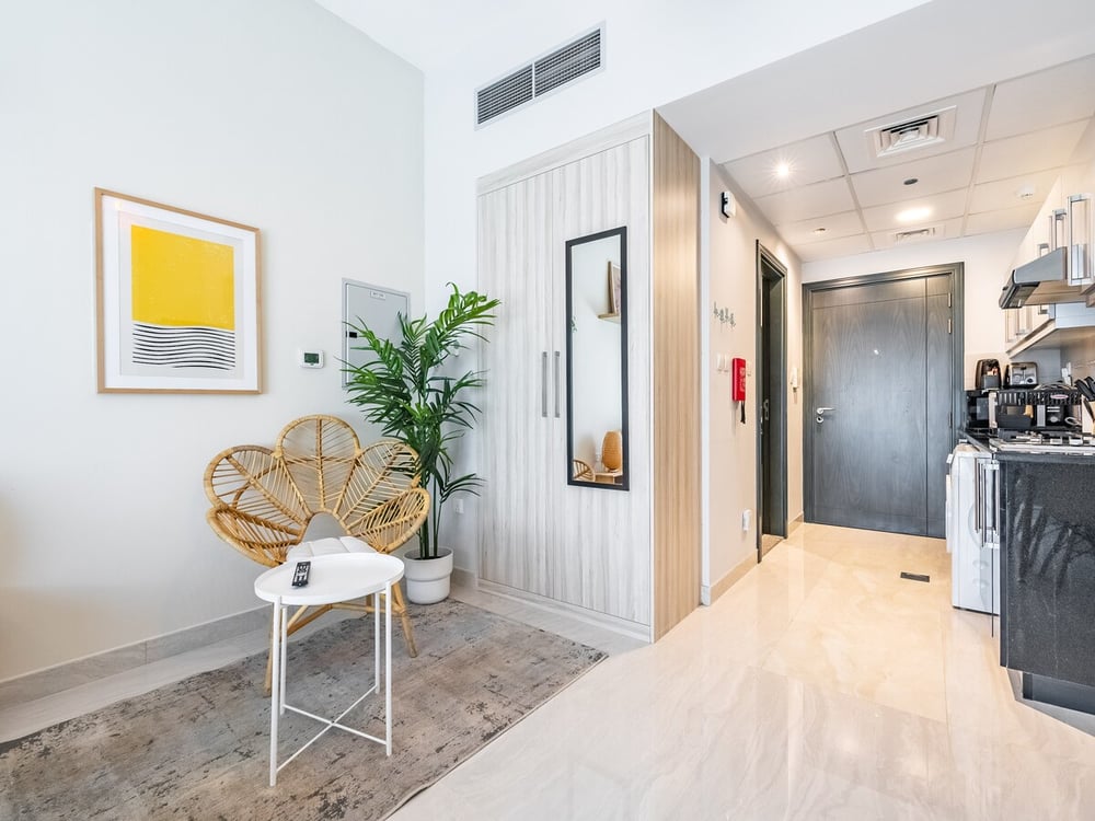 Studio entry area with rattan chair plant and kitchen view