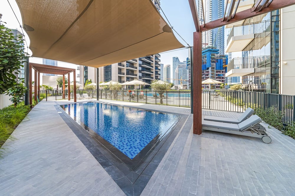Outdoor pool with sun lounger and shaded canopy in urban setting