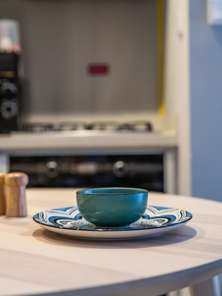 Close-up of dining table with bowl and hob in background
