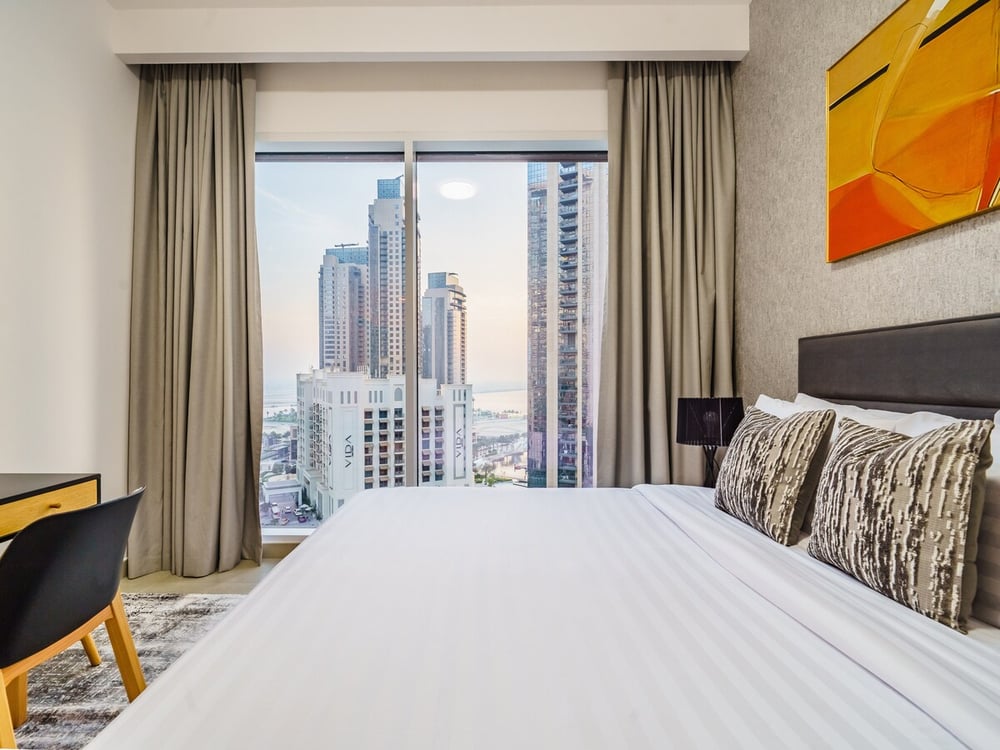 Bedroom with large window and city skyline view