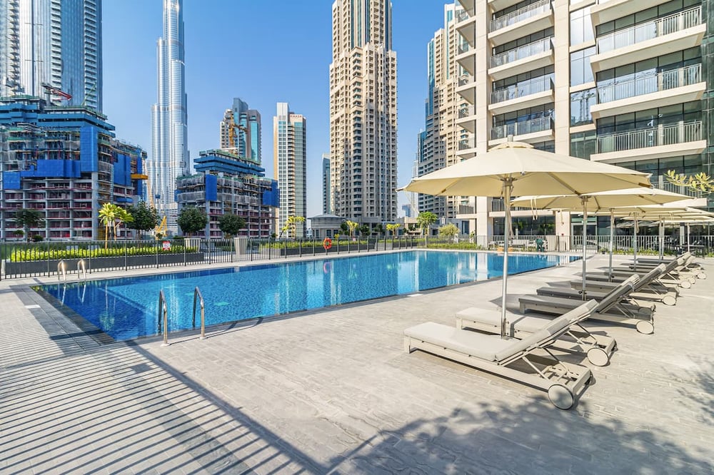 Outdoor swimming pool with sun loungers and city skyline backdrop