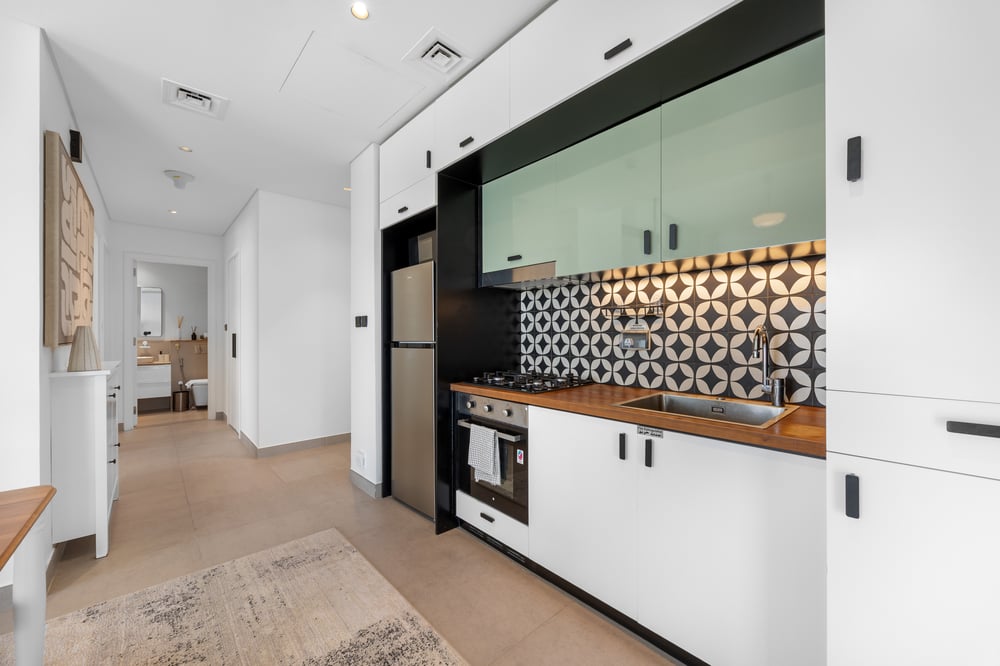 Kitchen corridor with fridge, oven, and wood countertop