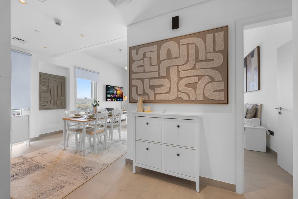 Dining area with white table and chairs, sideboard, and artwork