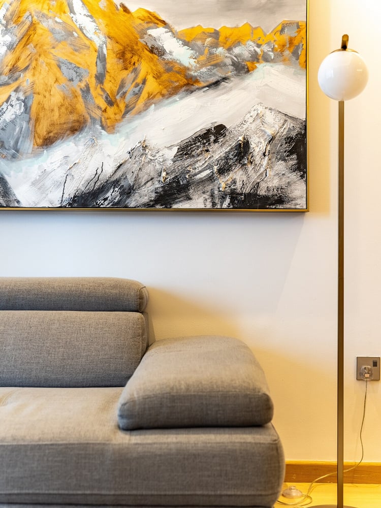 Close-up of sofa with mountain artwork and floor lamp