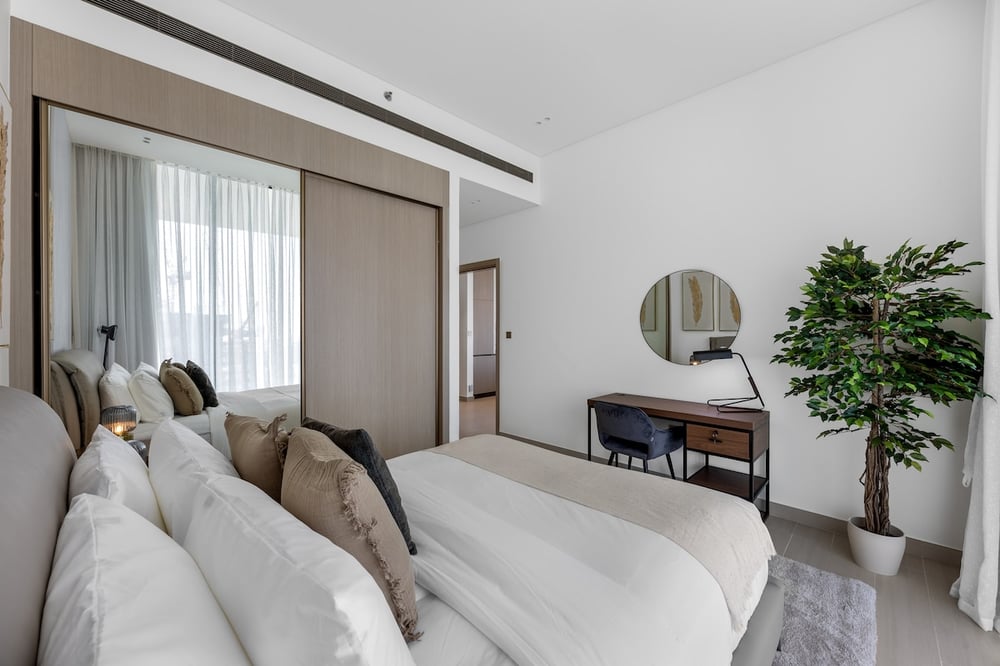 Bedroom with double bed, mirrored wardrobe and decorative plant
