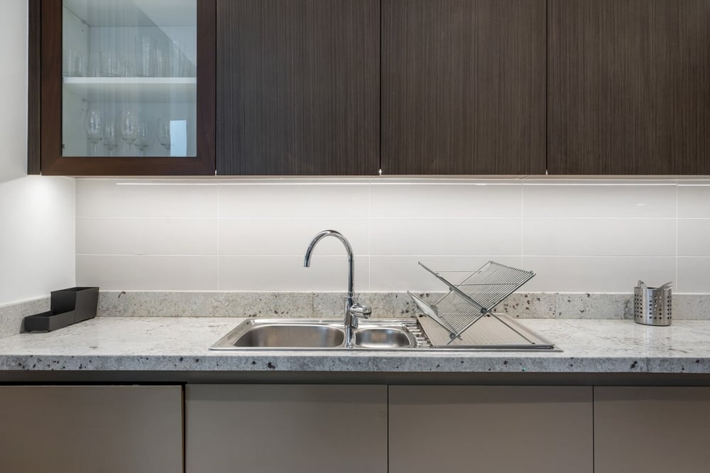 Kitchen sink with marble countertop and dark wood cabinets
