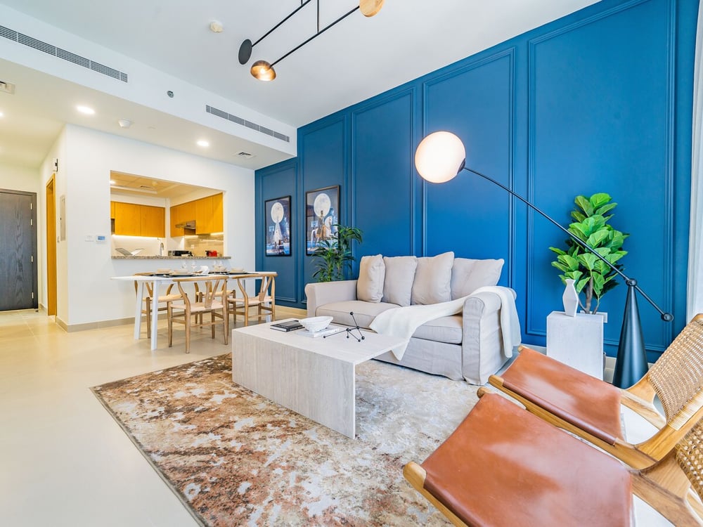 Open plan living room with blue wall and kitchen beyond