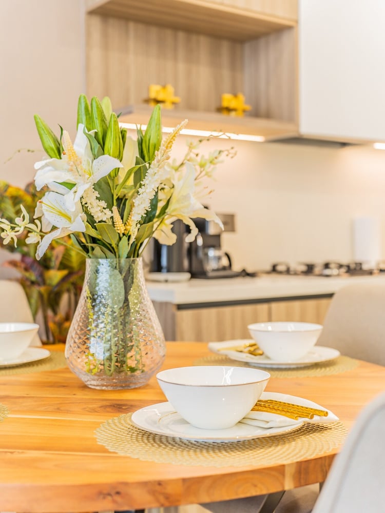 Dining table close-up with flowers cups and kitchen behind