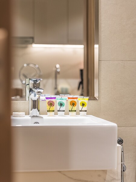 Bathroom sink with toiletries and lit mirror cabinet