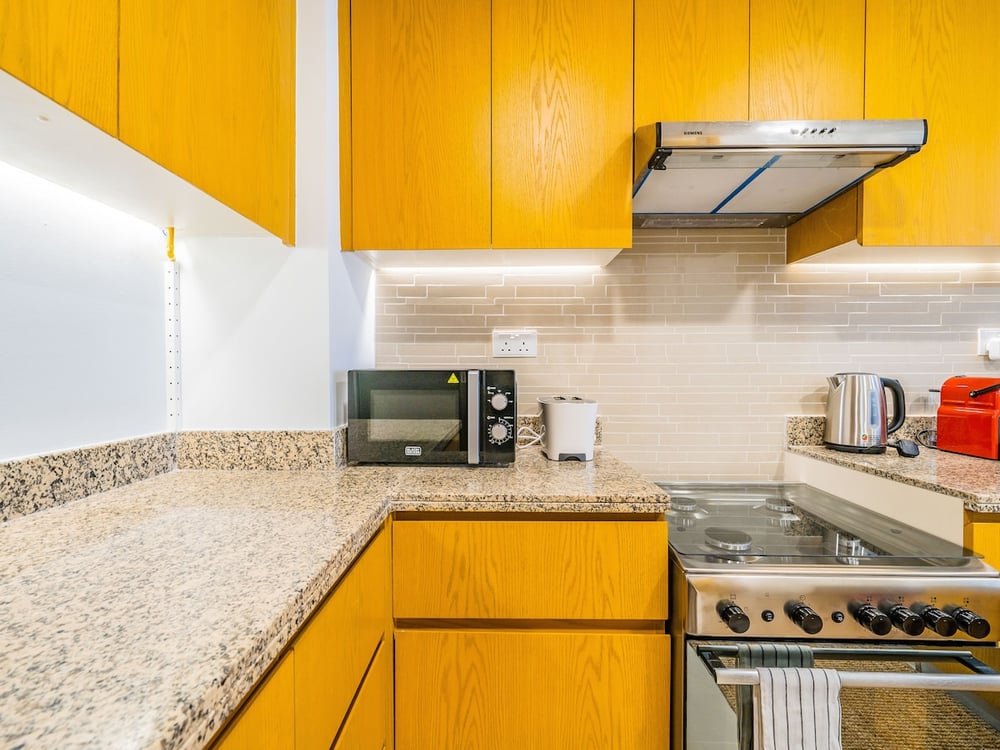Kitchen yellow cabinets microwave and kettle on counter