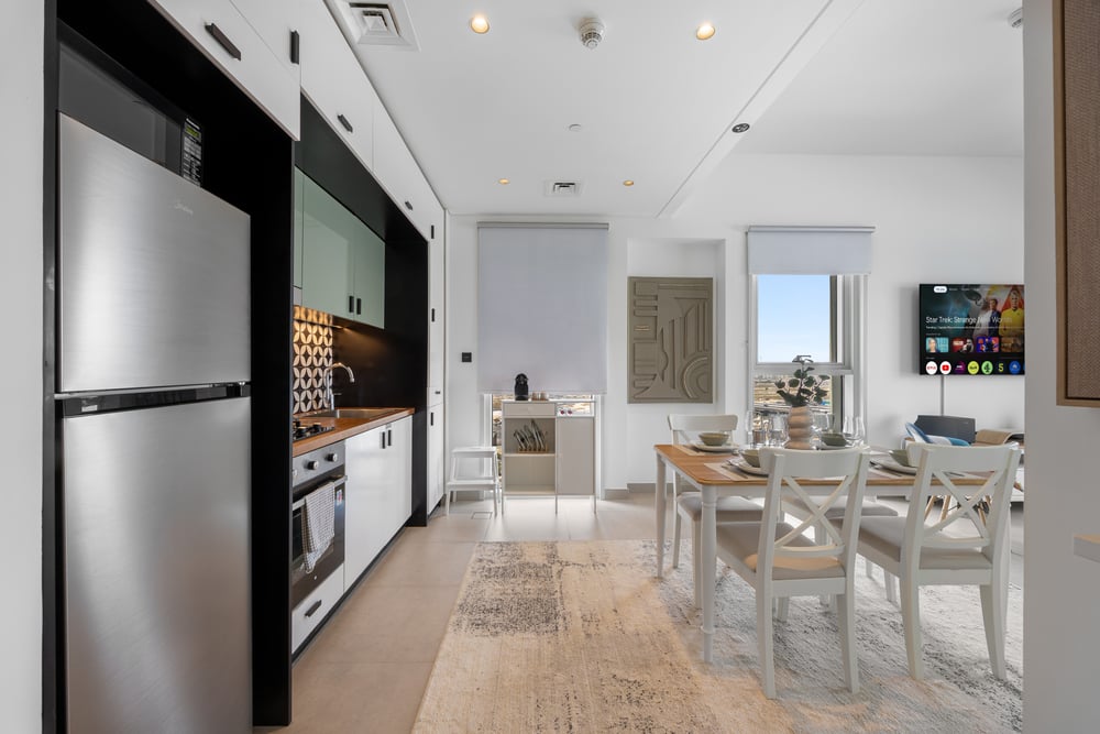 Open-plan kitchen with fridge, oven, and dining table
