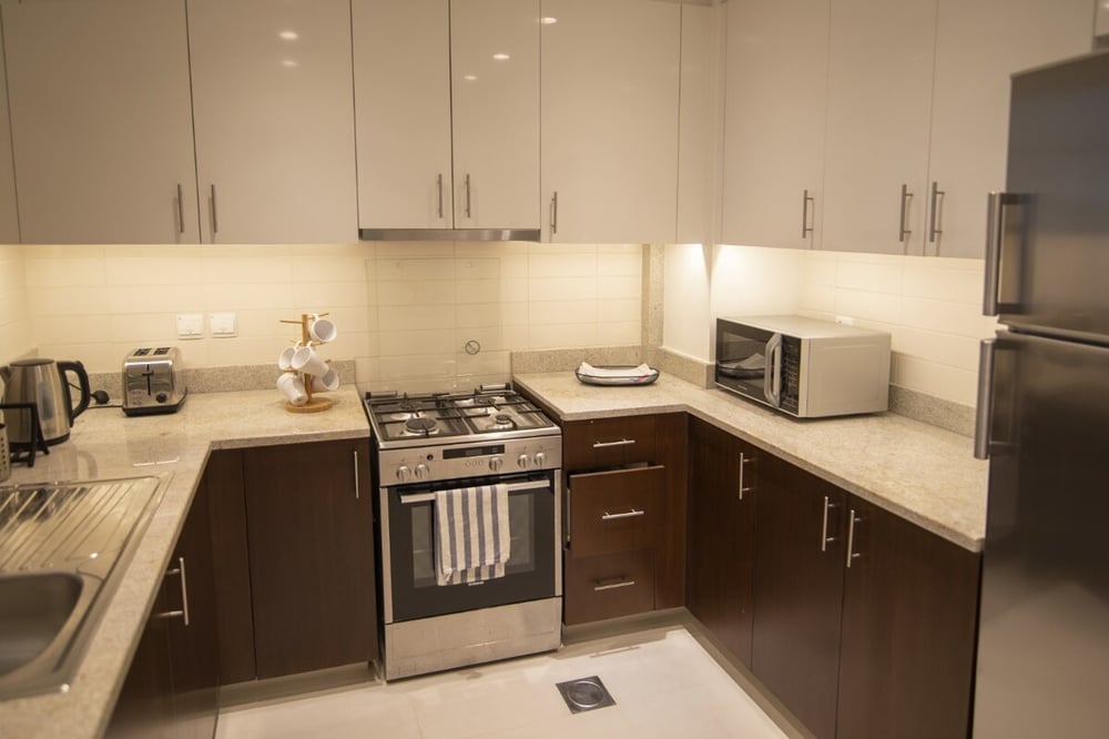 Kitchen with gas hob, oven, microwave, fridge and dark wood cabinets