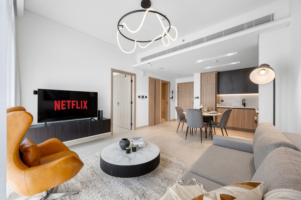 Living room with Netflix TV, sofa and dining area visible