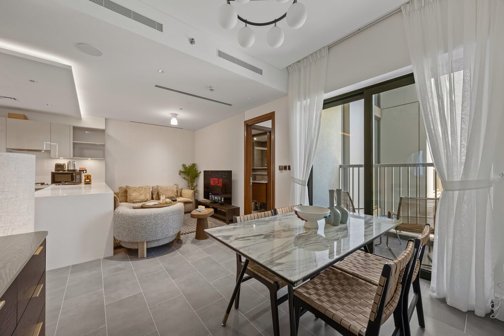 Dining and living area with balcony and kitchen in background