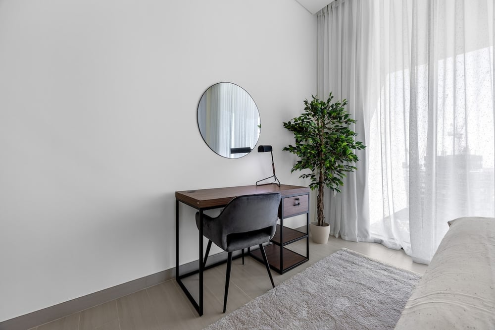 Bedroom desk area with round mirror and plant