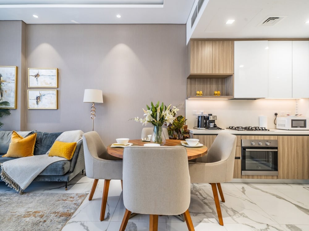 Dining area with round table and four chairs next to kitchen