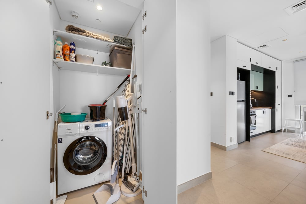 Laundry closet with washing machine, broom, and cleaning tools