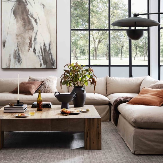 A neutral living room with a beige sofa, woven baskets, and wood side table.