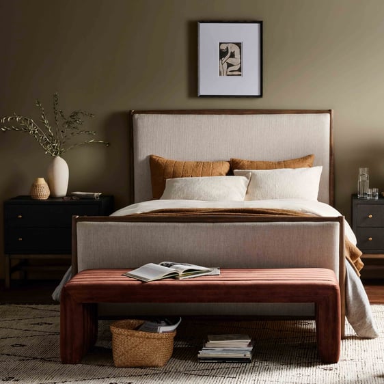Bedroom showcasing a soothing neutral color palette. The upholstered headboard takes center stage, accompanied by two matching black nightstands. A brown bench rests at the foot of the bed, while a beige rug ties the space together.