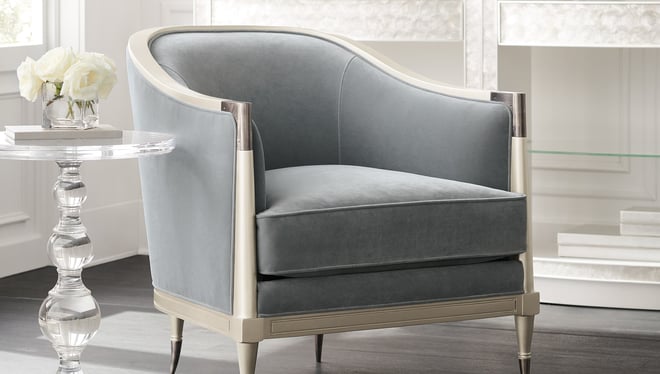 Gray blue upholstered Caracole armchair next to clear acrylic side table