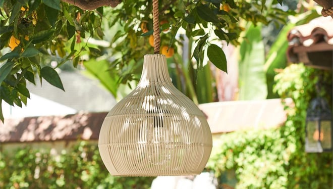 Rattan and rope pendant from Made Goods hanging in front of a fruit tree