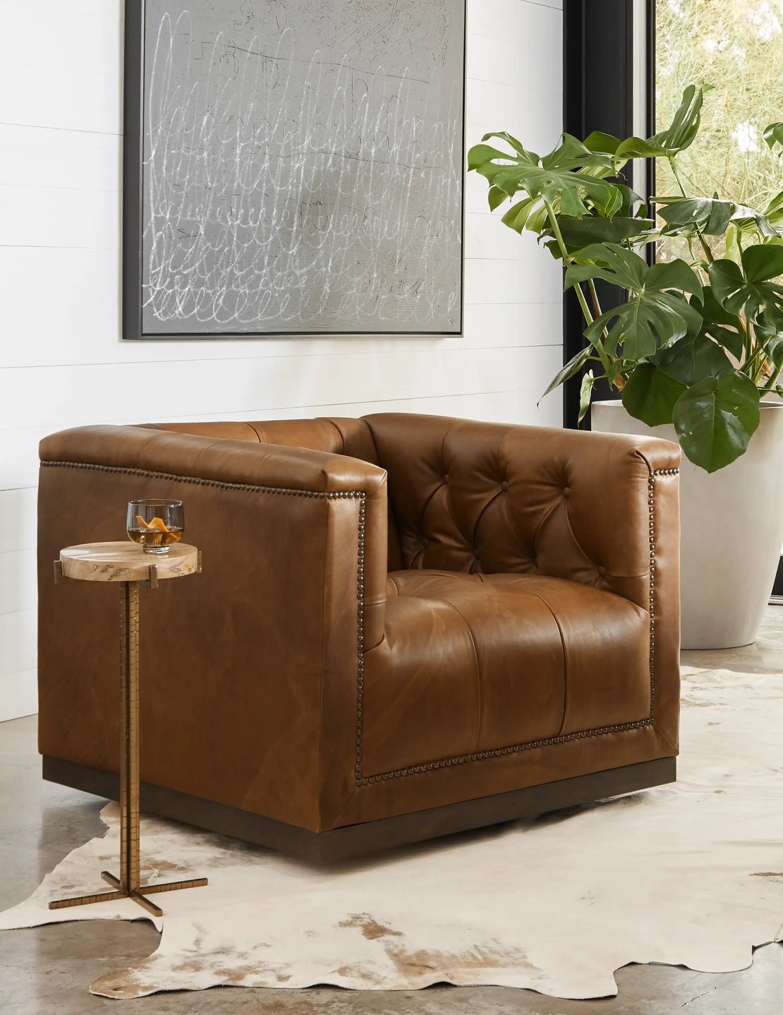 Leather arm chair next to a small brass and marble side table.