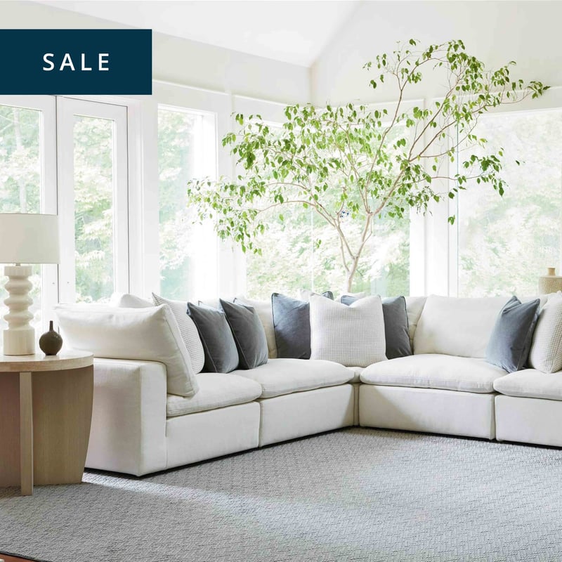 Elegant living room with large, white sectional and square glass topped coffee table