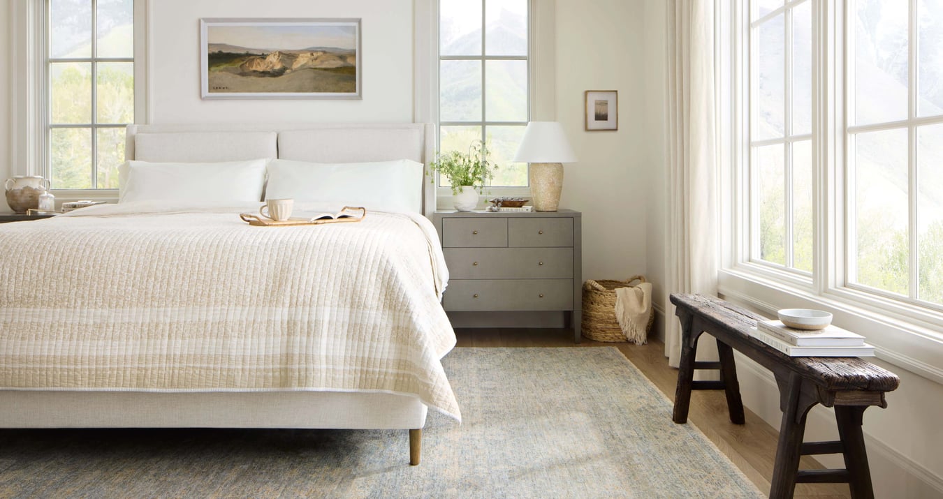 A bedroom with an upholstered bed and a dresser
