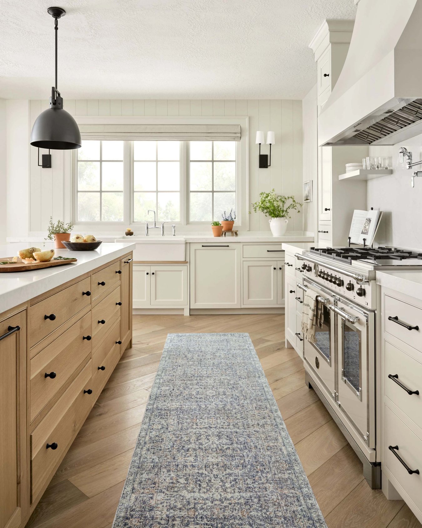 Bright kitchen with a blue runner rug in between a stove and kitchen island.