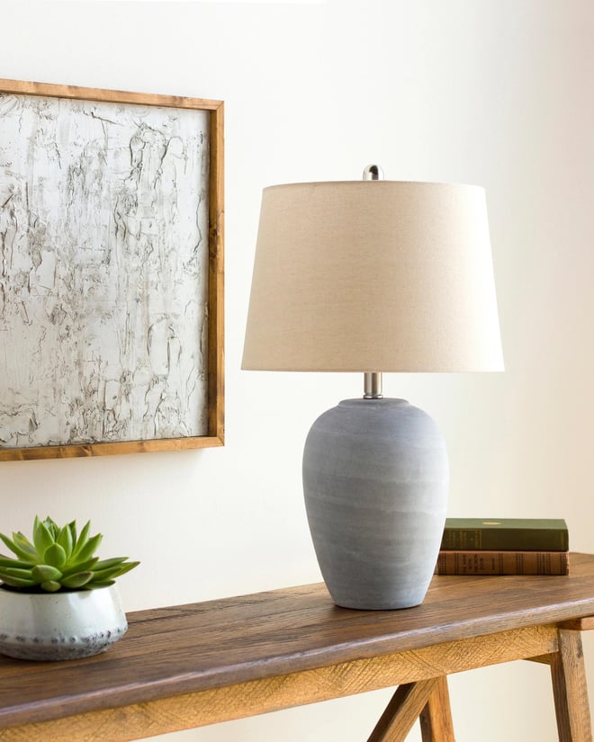 Ceramic table lamp on top of wood console table.