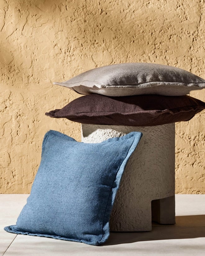 Stack of indoor/outdoor pillows on top of outdoor side table.