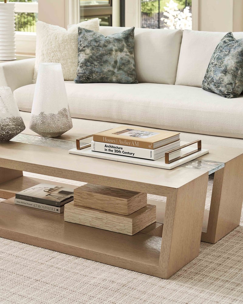 A cozy living room with a stylish light wood coffee table filled with decor.