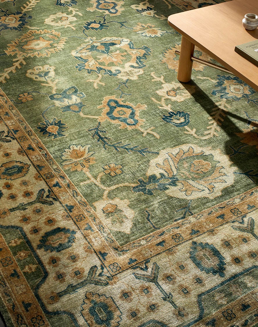 Close-up of a traditional green area rug with intricate floral patterns, adding rich color and timeless style to any space on a luxury rug website.
