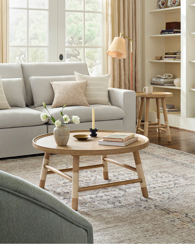 Light-filled living room with neutral sofa, round wood coffee table, and textured area rug