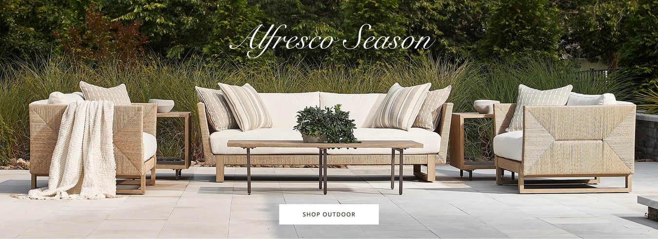 Outdoor patio seating with woven sofas, neutral cushions, and wood coffee table styled for alfresco living