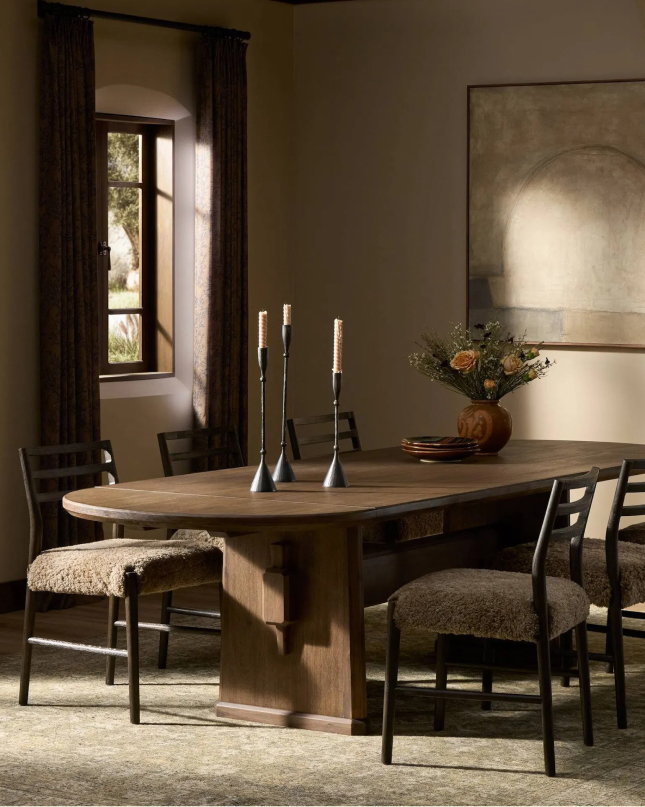 Warm dining room with wood table, upholstered chairs, and candle centerpiece.