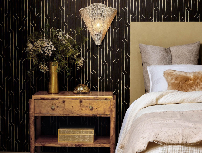 Bedroom with wood nightstand, woven wall sconce, and layered neutral bedding.