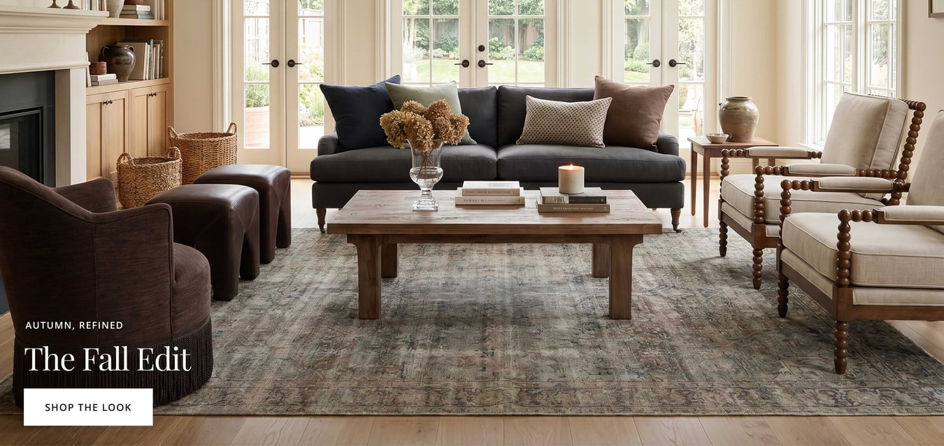 Warm fall living room with dark sofa, wood accents, neutral seating, and vintage-style rug.