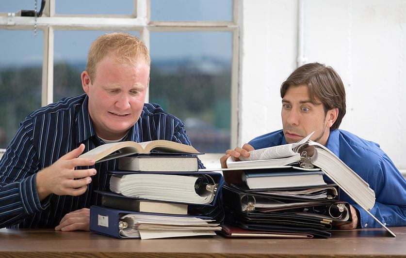 Businessmen faced with pile of notebooks